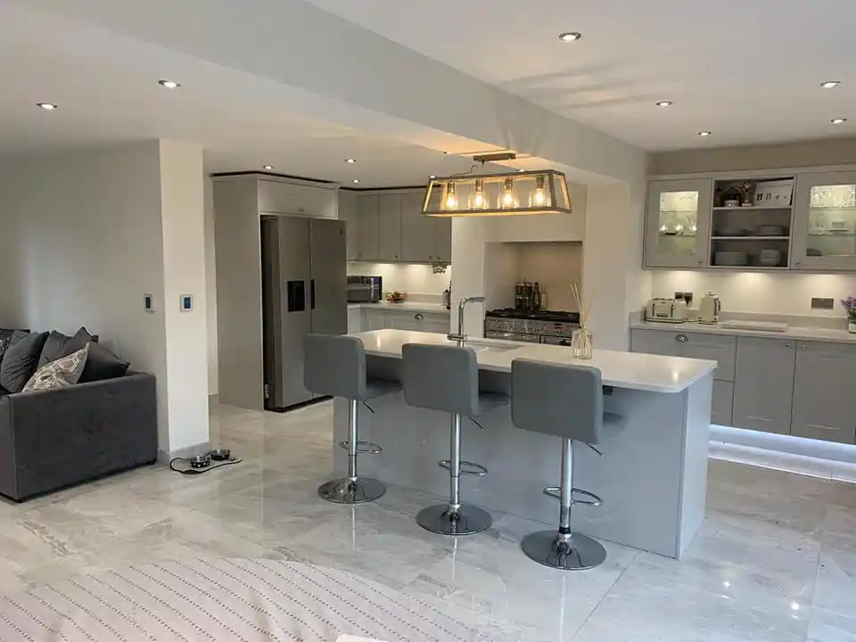 Modern Kitchen extension, with island and chairs, massive fridge, professional cooker, marble floors, modern kitchen units, and a grey sofa